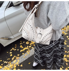 Détail du sac à bandoulière demi-lune beige avec clous argentés et boucle sur un mannequin