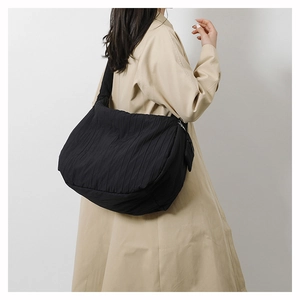Detail of the large capacity black quilted shoulder bag featuring pleated fabric texture