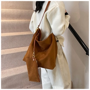 Detail of tan suede tote bag with matching zippered pouch and gold metal buckles