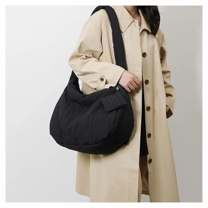 Detail shot of the pleated fabric texture and small zipper pouch on the black shoulder bag