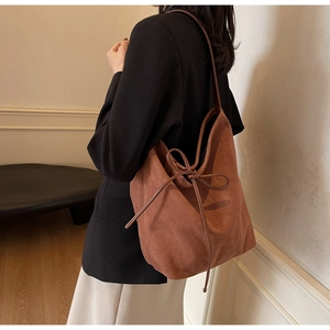 Detail of caramel suede tote bag featuring a decorative bow tie and large capacity