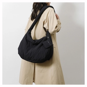Detail view of black pleated fabric tote bag with detachable square coin purse on strap