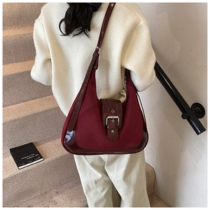 Detail of burgundy crescent shoulder bag with matte leather and glossy buckle strap