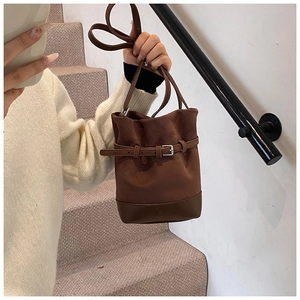 Detail of vintage dark brown bucket bag with matte texture and decorative belt buckle
