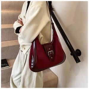 Close-up of burgundy suede and smooth leather saddle bag with silver buckle detail