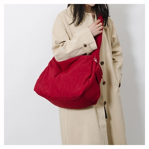 Detail of red pleated canvas tote showing textured fabric and wide shoulder strap