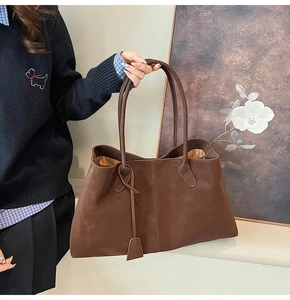 Detailed view of dark brown suede tote bag with matte texture and minimalist square tag