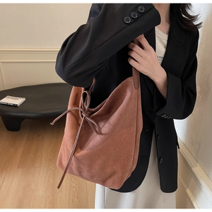 Detail of a brown suede tote bag with decorative side bow knot for a minimalist look