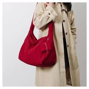 Detail of red oversized hobo bag featuring vertical pleats and matching coin purse charm