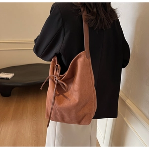 Detail showing the brown suede bucket bag with a stylish side knot on a model