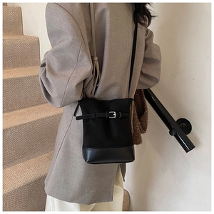 Detail of black bucket bag with silver buckle and leather drawstring on stair background