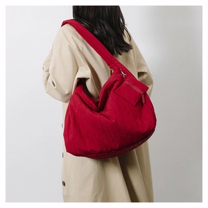 Detail of red quilted crossbody bag featuring a large capacity design and a small coin pouch