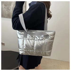 Detailed shot of metallic silver puffer tote bag with quilted pattern and wide strap