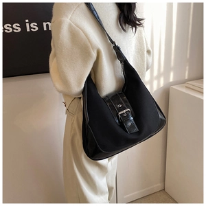 Detail of black patchwork shoulder bag with glossy leather and silver metal buckle