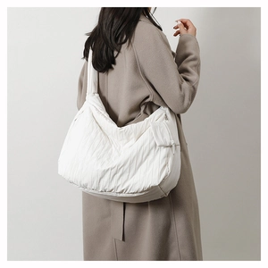 Side view of model wearing a large white quilted tote bag with vertical pleated texture