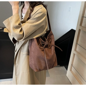 Close-up of brown suede nylon tote bag with decorative bow and leather strap