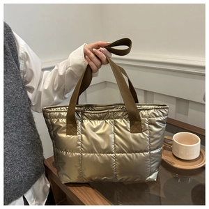 Detail of champagne gold quilted tote bag with brown woven handles in a modern setting