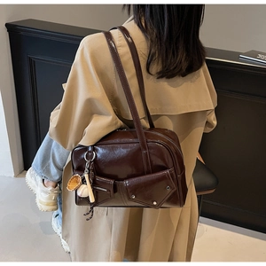 Détail d'un sac à bandoulière marron foncé vintage avec deux poches frontales fonctionnelles