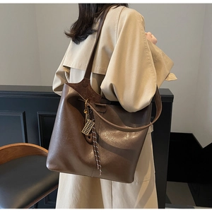 Detail of a large brown tote bag with metallic finish and creative abacus pendant accessory