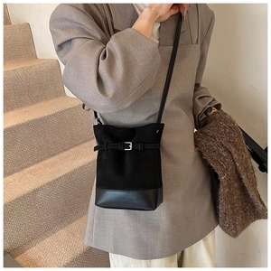Close-up of black matte leather bucket bag with suede texture and belt buckle detail