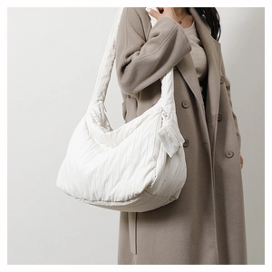 Quilted white puffer tote bag with matching pouch shown on shoulder with winter coat