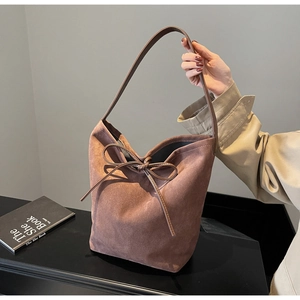 Detail of dark brown suede drawstring bucket bag with decorative bow and leather strap