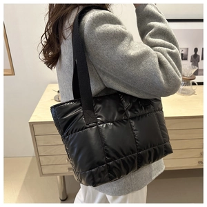 Macro detail of black quilted puffy tote bag with premium nylon texture and shoulder strap