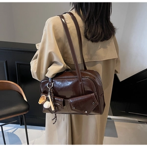 Détail du sac cabas en cuir PU marron foncé brillant avec poches et breloques de sport