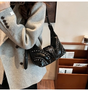 Détail d'un sac à bandoulière punk noir en forme de croissant avec rivets argentés