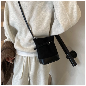Fashionable black matte leather bucket bag with buckle detail shown on model in grey studio