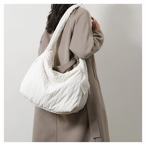 Detail of white quilted puffy shoulder bag with matching mini zipper pouch on strap