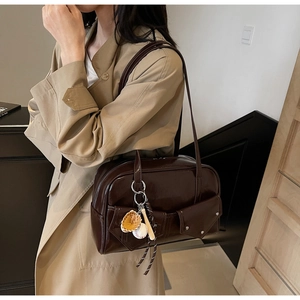Détail du sac en cuir verni café avec breloques de sport et boutons-pression métalliques