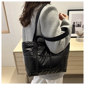 Detail of a large black glossy quilted tote bag made of high-quality padded space cotton fabric