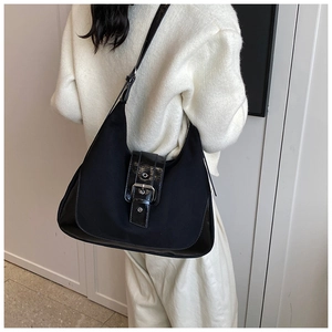 Detail of the black crescent shoulder bag with silver metallic buckle on a model
