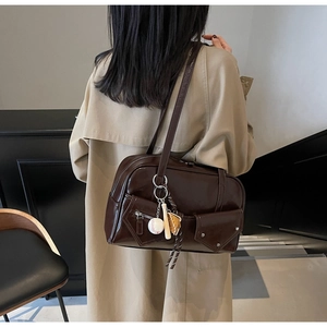 Détail d'un sac à bandoulière en PU marron foncé brillant avec poches avant et rivets