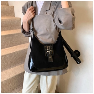 Close-up of black suede and patent leather shoulder bag with vintage silver buckle