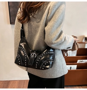Détail d'un sac à bandoulière noir vintage avec rivets et boucles métalliques argentées