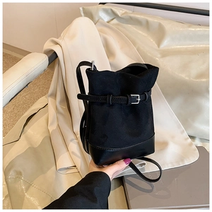 Close-up of black bucket bag featuring matte suede and smooth leather with silver buckle