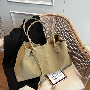 Minimalist olive green suede tote bag with slim shoulder straps on a wooden chair