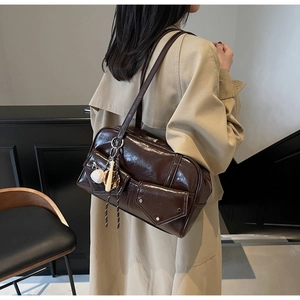 Détail du sac à bandoulière marron foncé avec poches utilitaires et breloque baseball