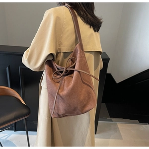 Chic brown suede bucket bag with drawstring closure shown on shoulder for daily wear