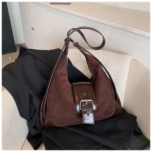 Retro dark brown matte leather hobo bag with buckled strap on a white sofa backdrop