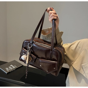 Détail du sac bandoulière en cuir marron brillant avec poches et charm de baseball
