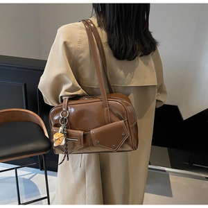 Détail d'un sac à épaule en cuir verni marron vintage avec un ours en peluche sur un modèle