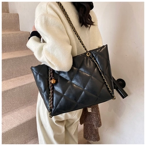 Detail of black quilted PU leather tote bag with chain strap and gold ball ornament