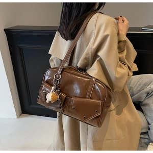 Détail du sac à bandoulière en PU marron brillant avec rivets et pendentif de baseball