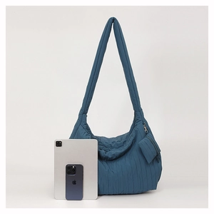 Detail of navy blue pleated shoulder bag shown with tablet for size comparison