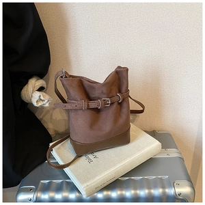 Brown matte leather bucket bag with decorative buckle and strap in a vintage style