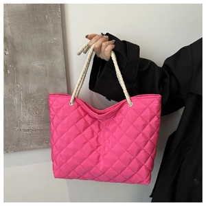 Détail du sac cabas matelassé rose vif montrant des poignées en corde et des coutures
