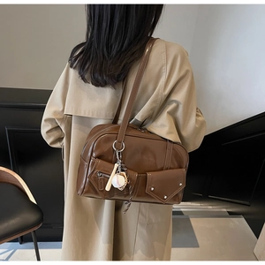 Détail d'un sac en cuir PU marron avec poches avant à rabat et pendentif de baseball